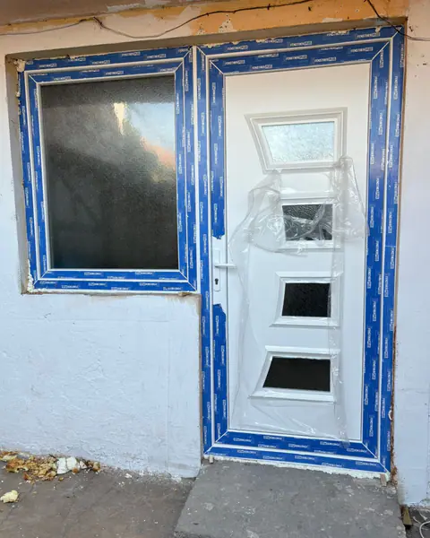 Бела влезна врата со декоративно стакло и прозорец од левата страна